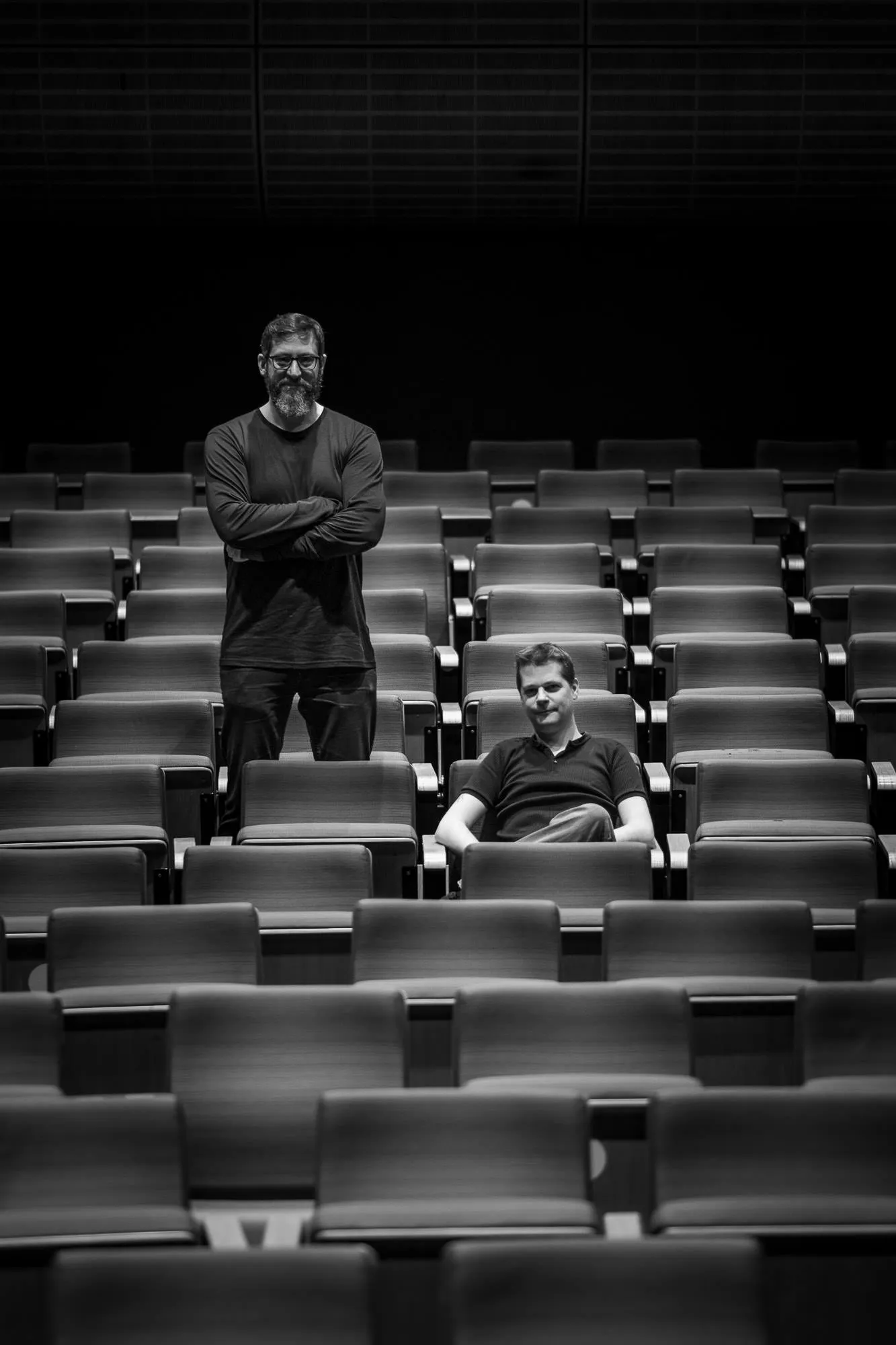 Two members of the team alone in the empty rows, one standing, one sitting