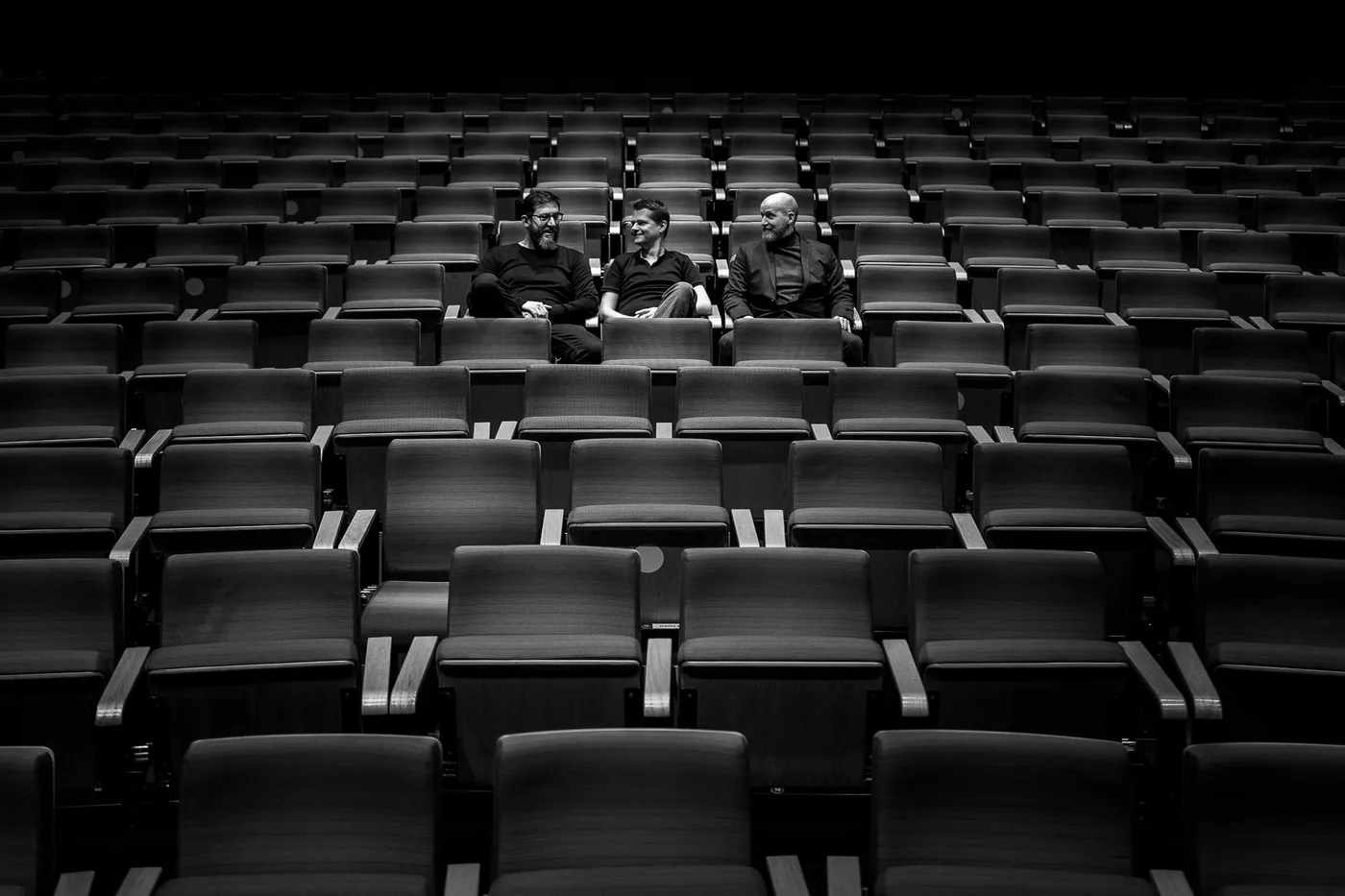 The empty auditorium, three members of the team sitting in its middle rows