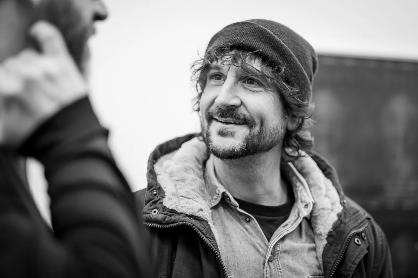 A guest in a beanie smiling in the crowded foyer