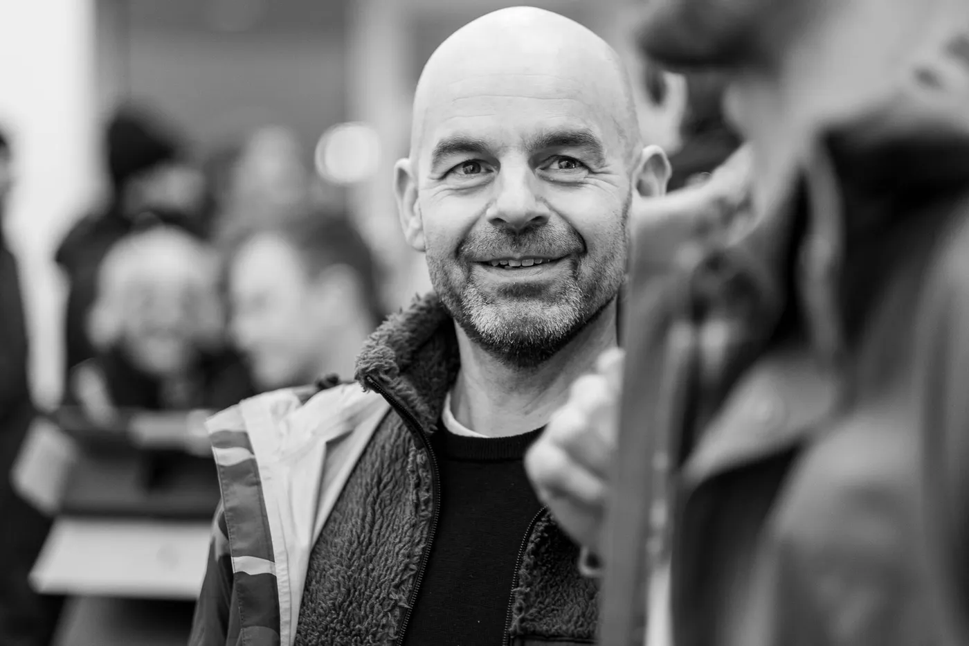 A team member with a grey beard smiling in the busy foyer