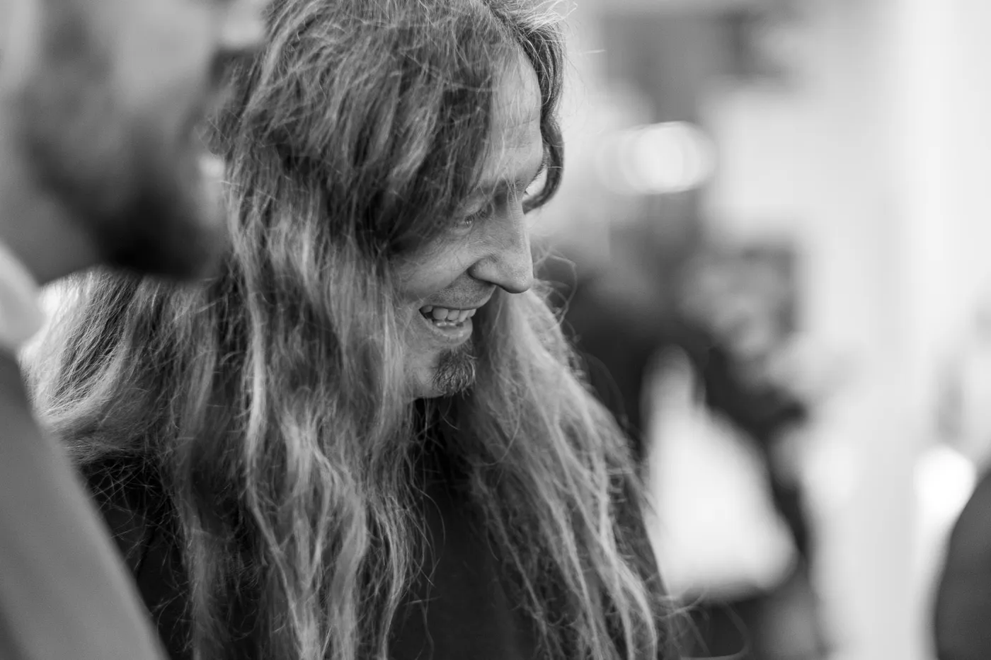 A long-haired guest laughing with lowered head in the foyer
