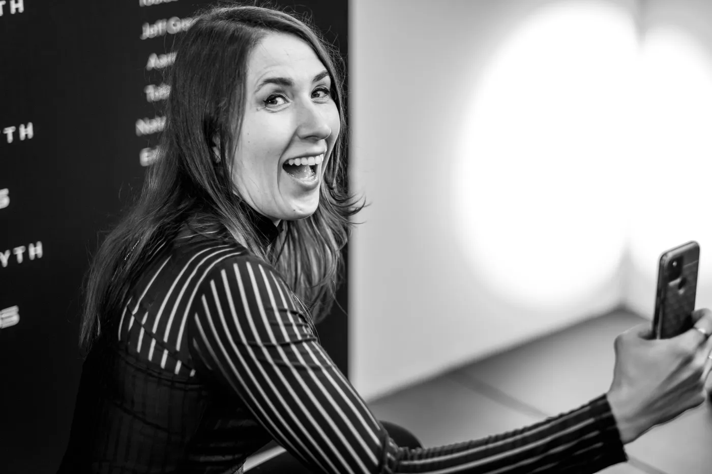 A guest taking a selfie in front of the credits wall, laughing
