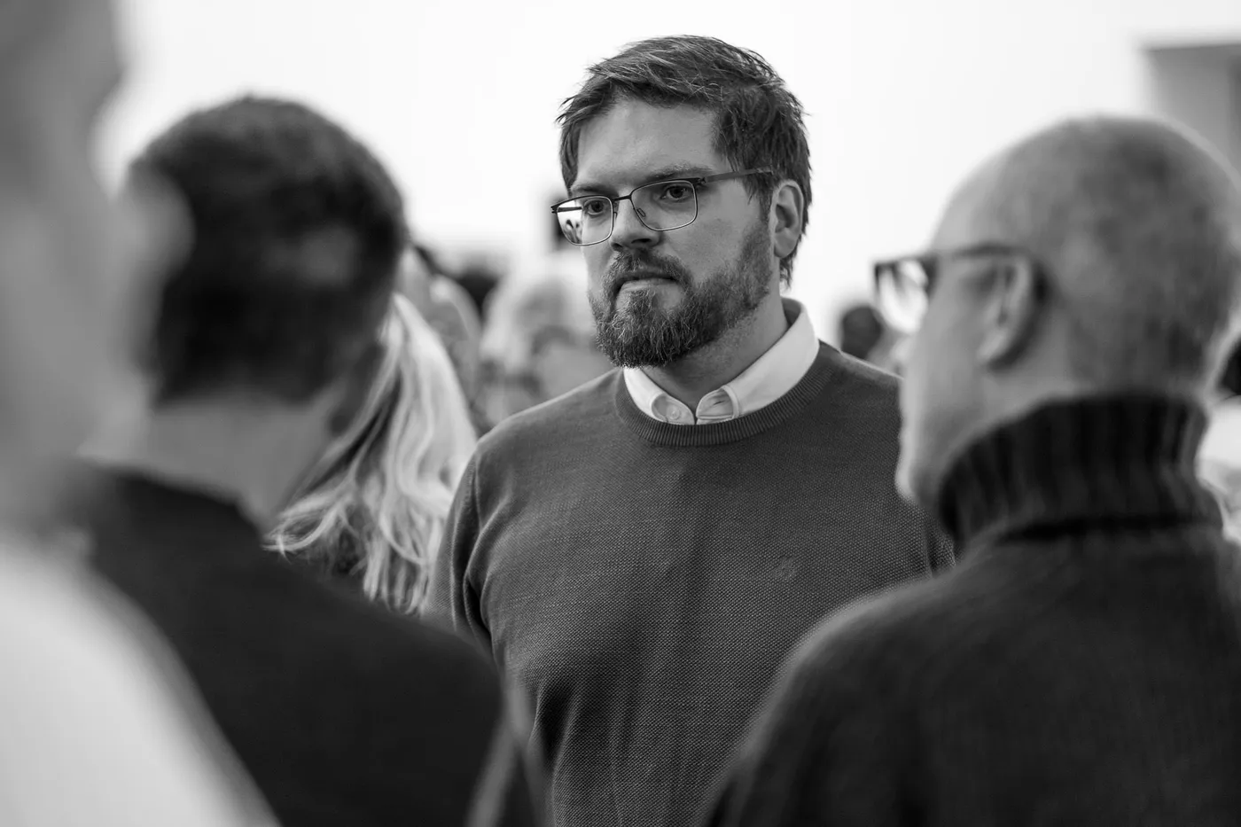 A guest with glasses listening in a conversation in the foyer