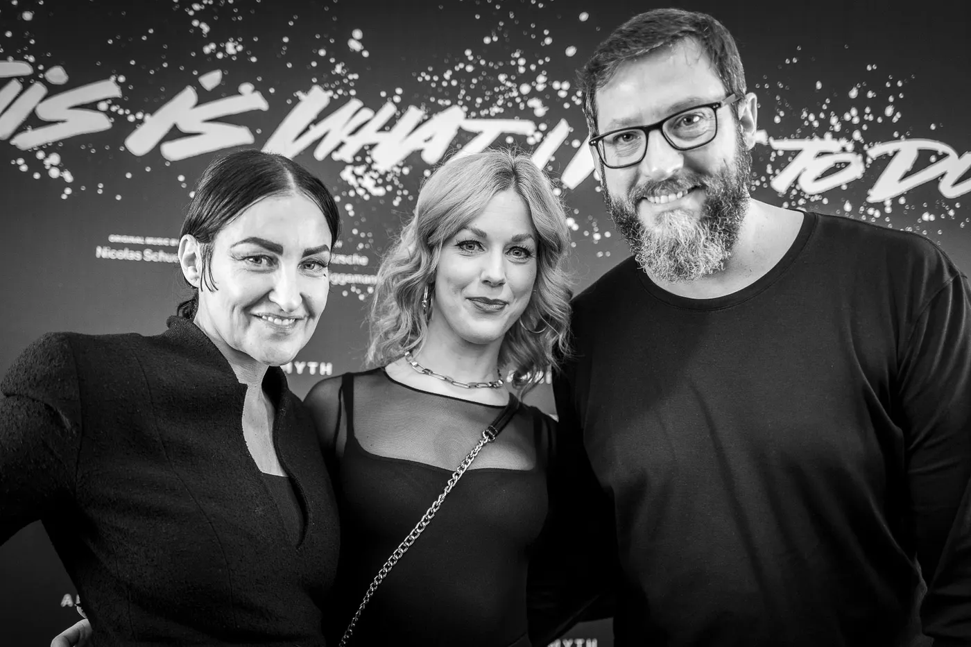 Four people posing in front of the lettering wall