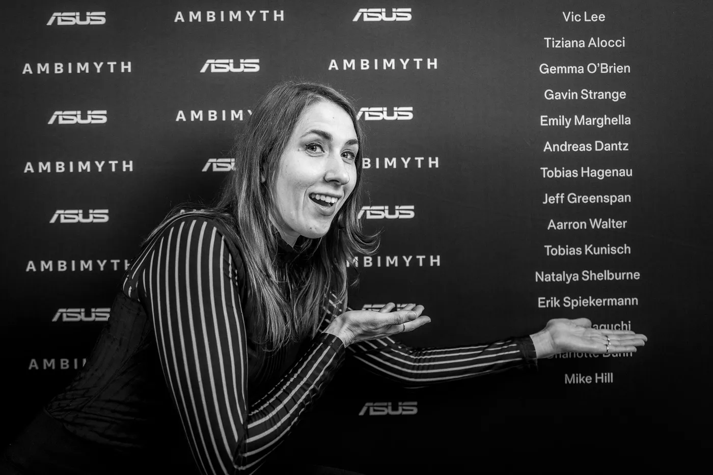 A guest gesturing at the names on the backdrop wall