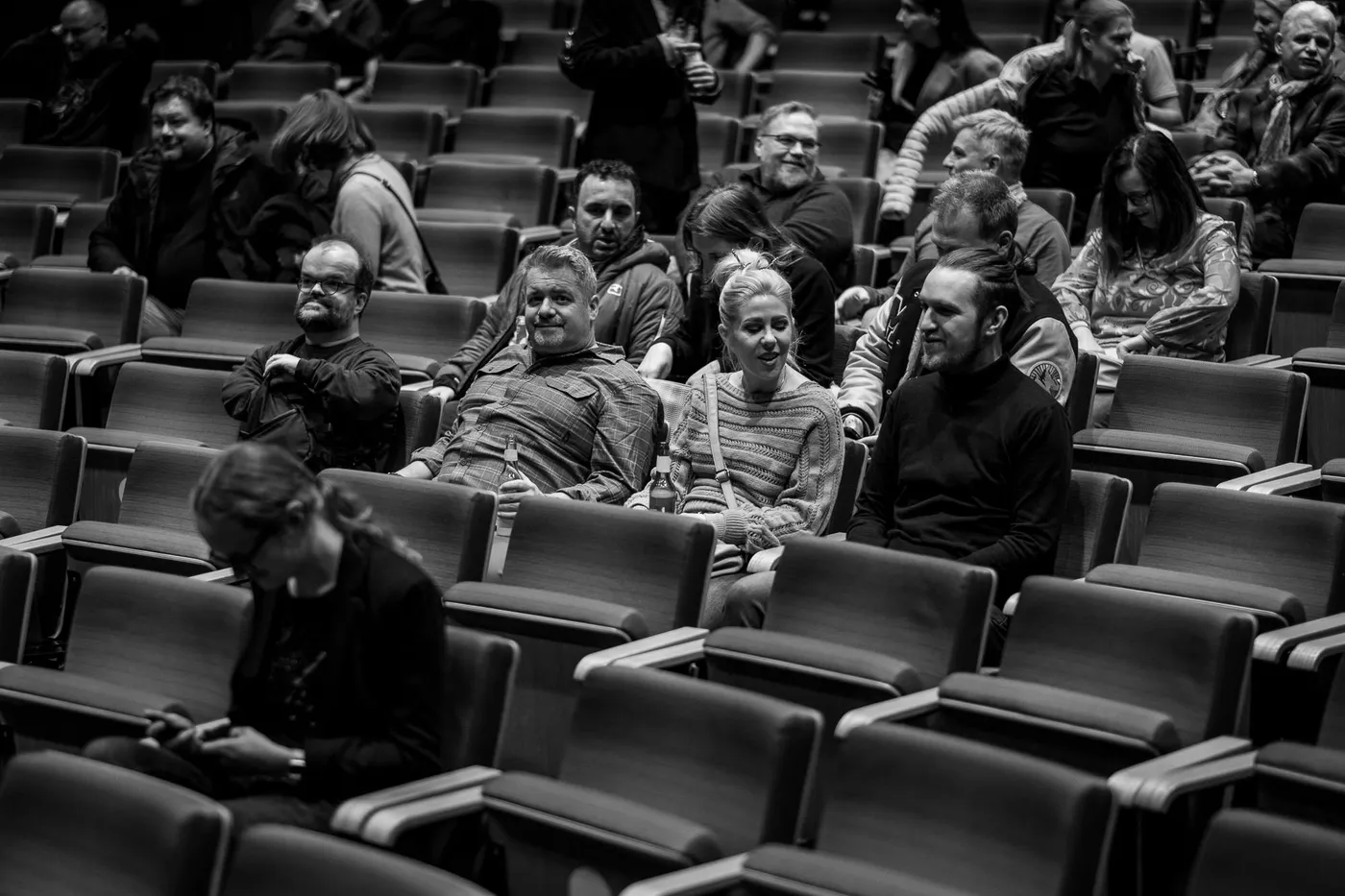 Guests in the rows seen from the front, some turned to one another, others still finding a seat