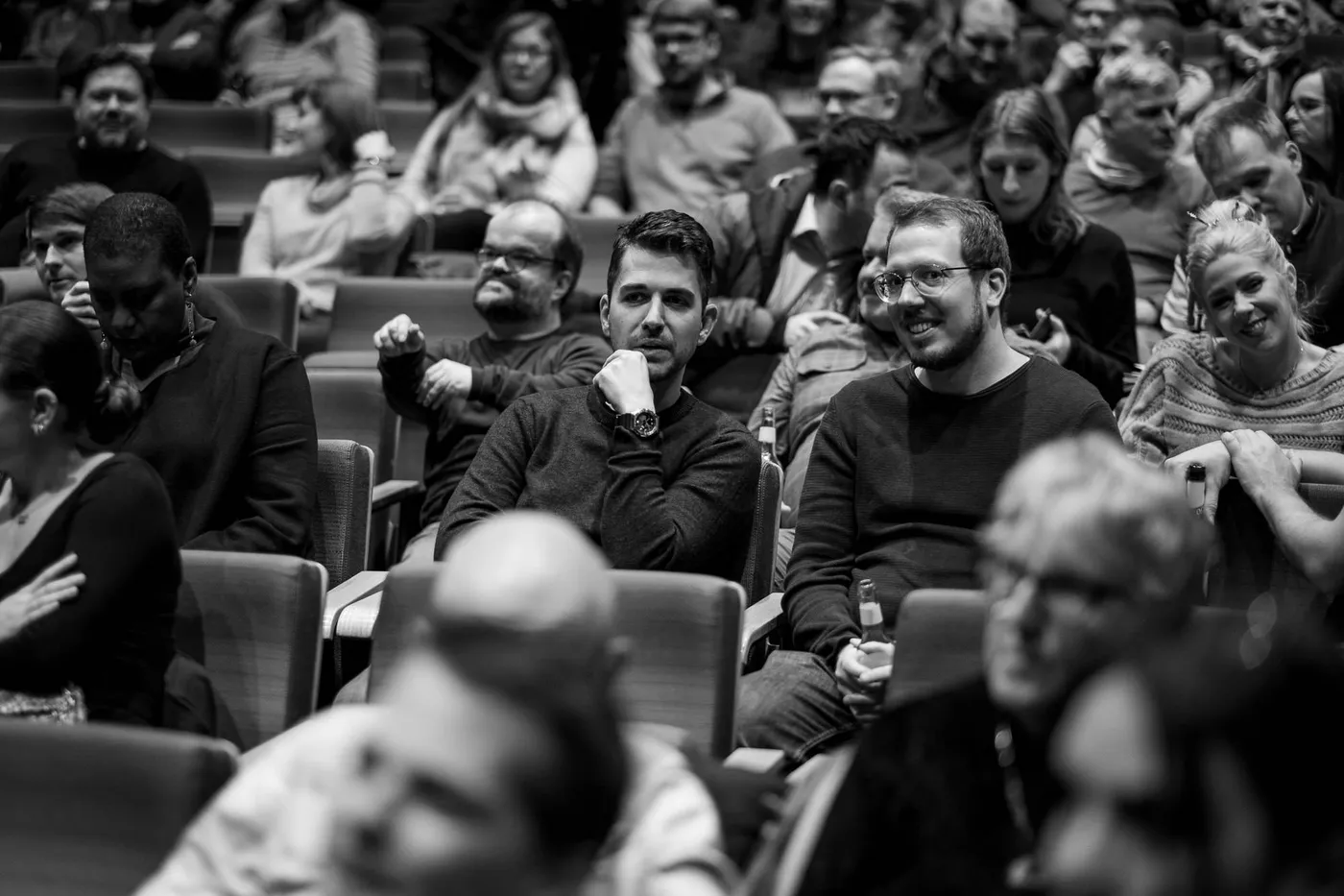 Packed rows close in the frame, faces in every direction, no empty seat in sight