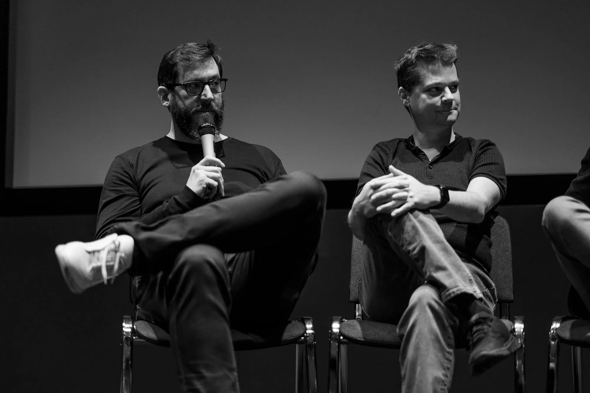 Two filmmakers on stage at the Q&A, one speaking into the microphone
