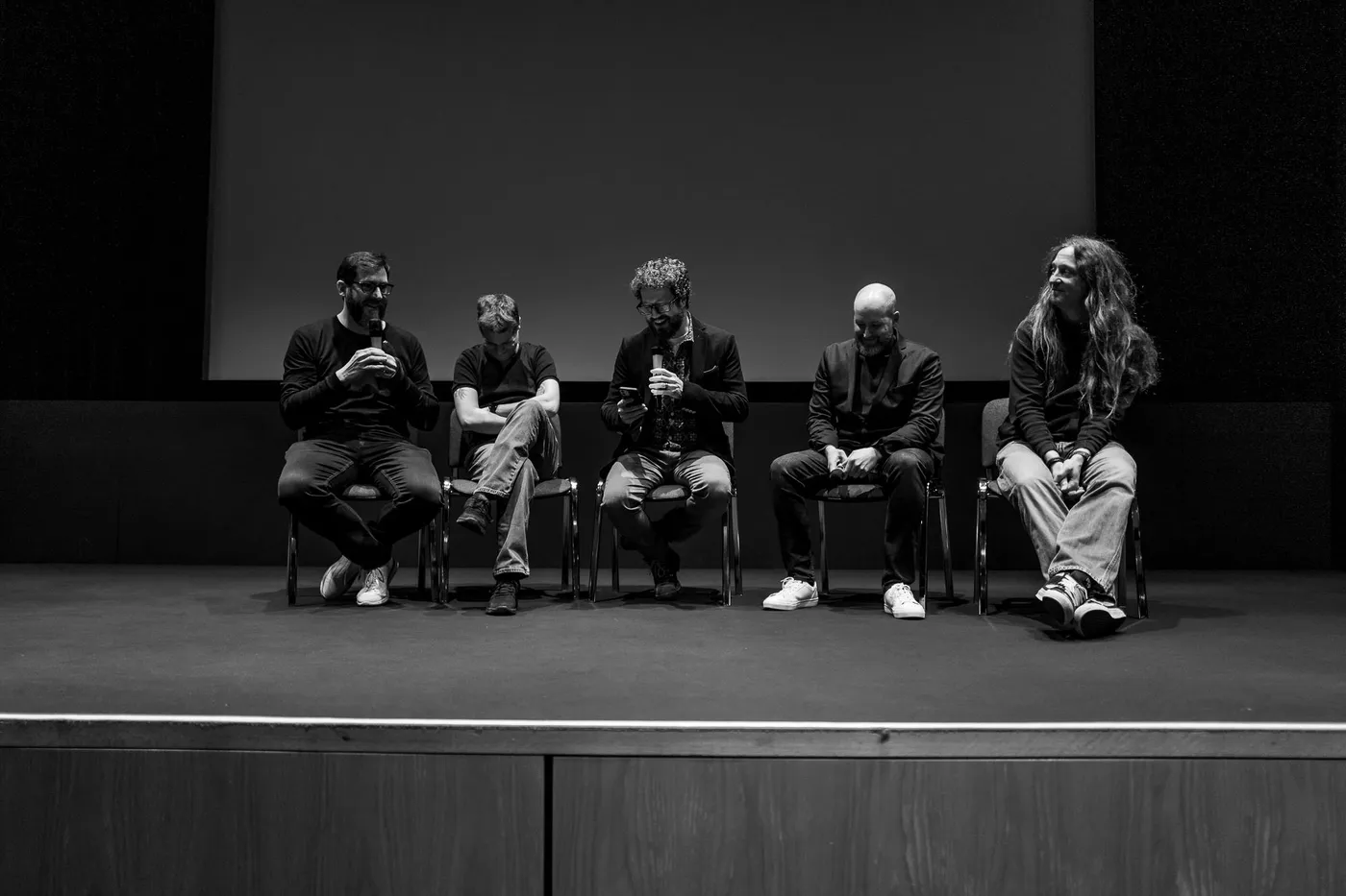 Five panel guests seated in a row on the stage for the Q&A