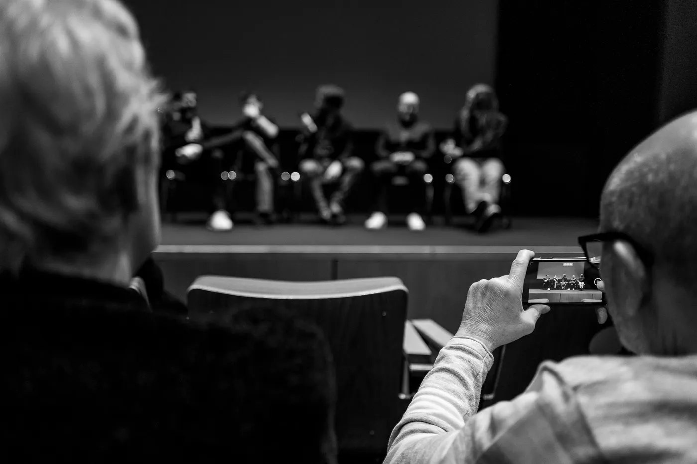 Two people in the front row, one filming the Q&A panel on a phone